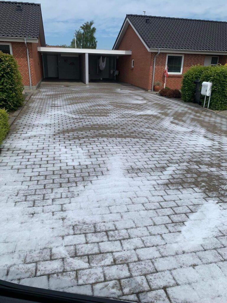 Rødt murstenshus med belagt indkørsel og carport